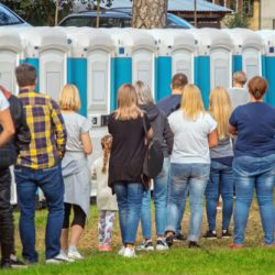 Group,Of,People,Standing,Near,Portable,Toilets,In,A,Park